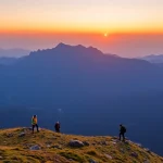 Tres personas en una cima montañosa al atardecer