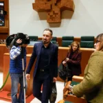 Personas en un salón de actos con cámaras y asientos verdes