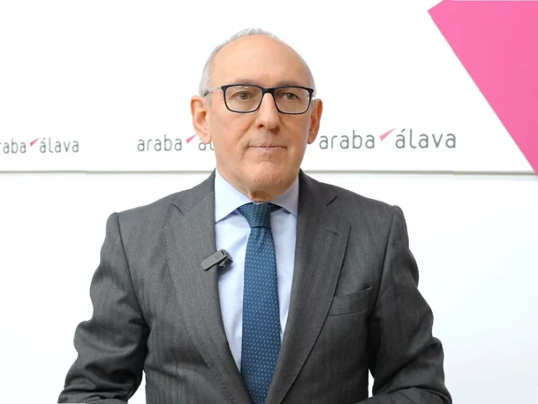 Hombre con traje y corbata frente a un fondo institucional.