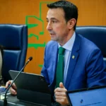 Hombre en traje azul hablando en una reunión con documentos