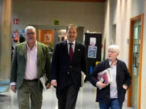 Tres personas caminando por un pasillo de un edificio