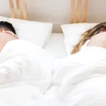Pareja durmiendo en camas separadas, cada uno en su lado.