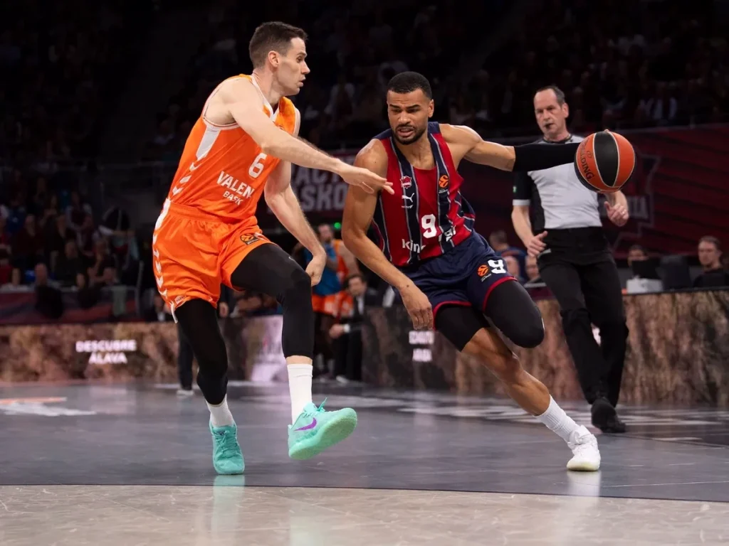 Jugador de Kosner Baskonia driblando ante rival de Valencia Basket