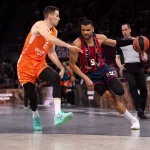 Jugador de Kosner Baskonia driblando ante rival de Valencia Basket