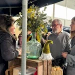Mujer conversando con dos personas en un mercado de trufas