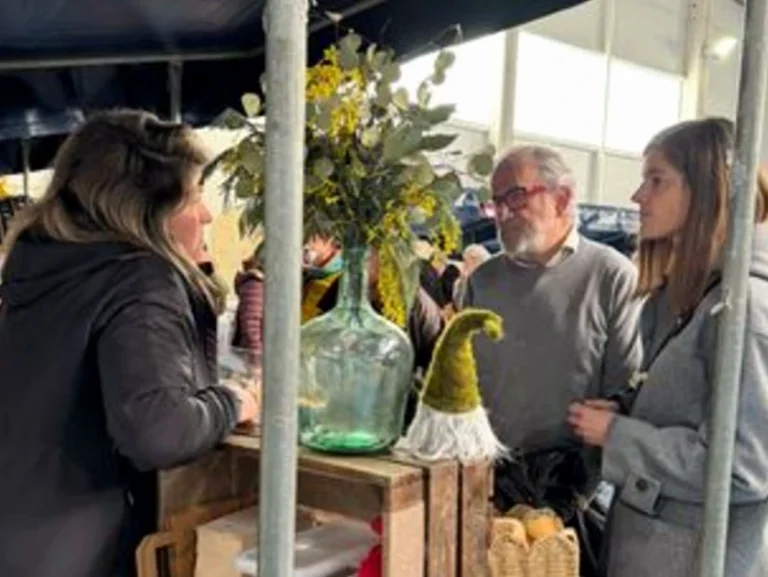 Mujer conversando con dos personas en un mercado de trufas