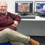 Investigador sentado frente a dos monitores mostrando Marte