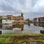 Terreno en Laguardia con agua estancada y edificios al fondo