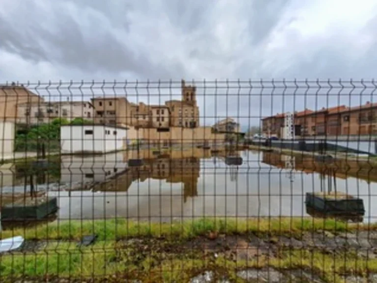 Terreno en Laguardia con agua estancada y edificios al fondo