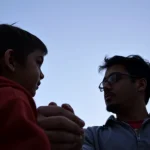 Silhouette de un niño y un adulto en un fondo azul claro.