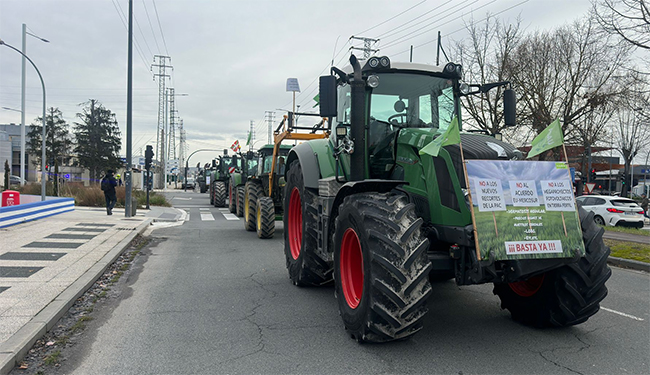 Tractores en fila en una carretera con pancartas