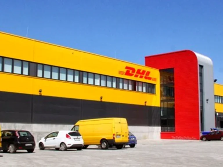 Edificio de DHL con vehículos estacionados frente a él