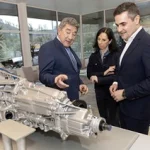 Tres personas observan un motor en la planta de Schaeffler en Elgoibar.