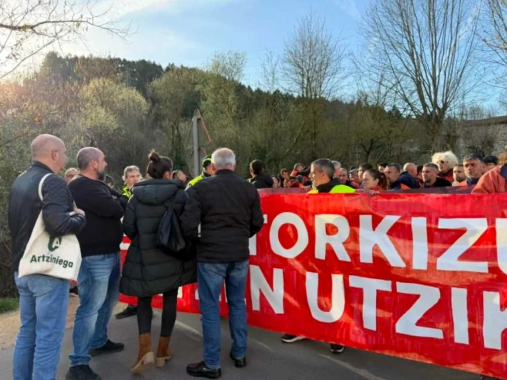 Grupo de personas protestando con pancarta roja en Aiaraldea.