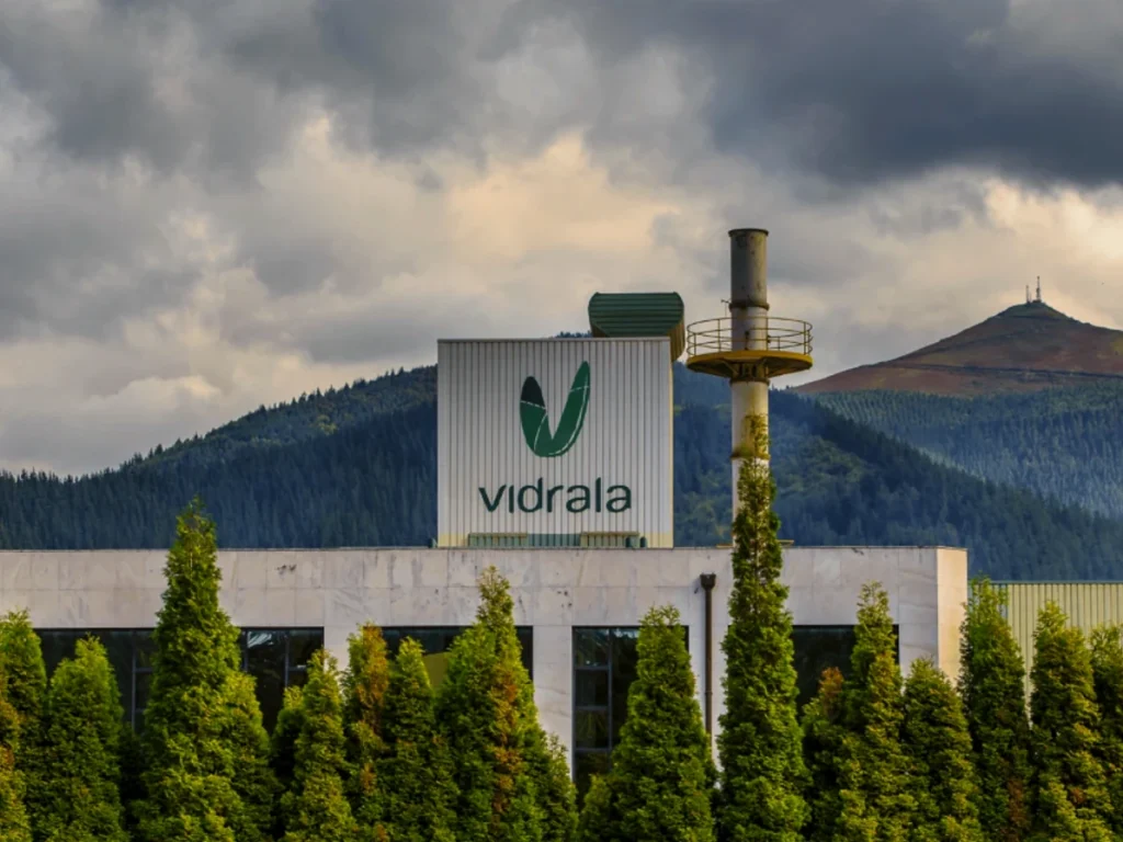 Fábrica de Vidrala con montañas al fondo y nubes oscuras
