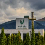 Fábrica de Vidrala con montañas al fondo y nubes oscuras