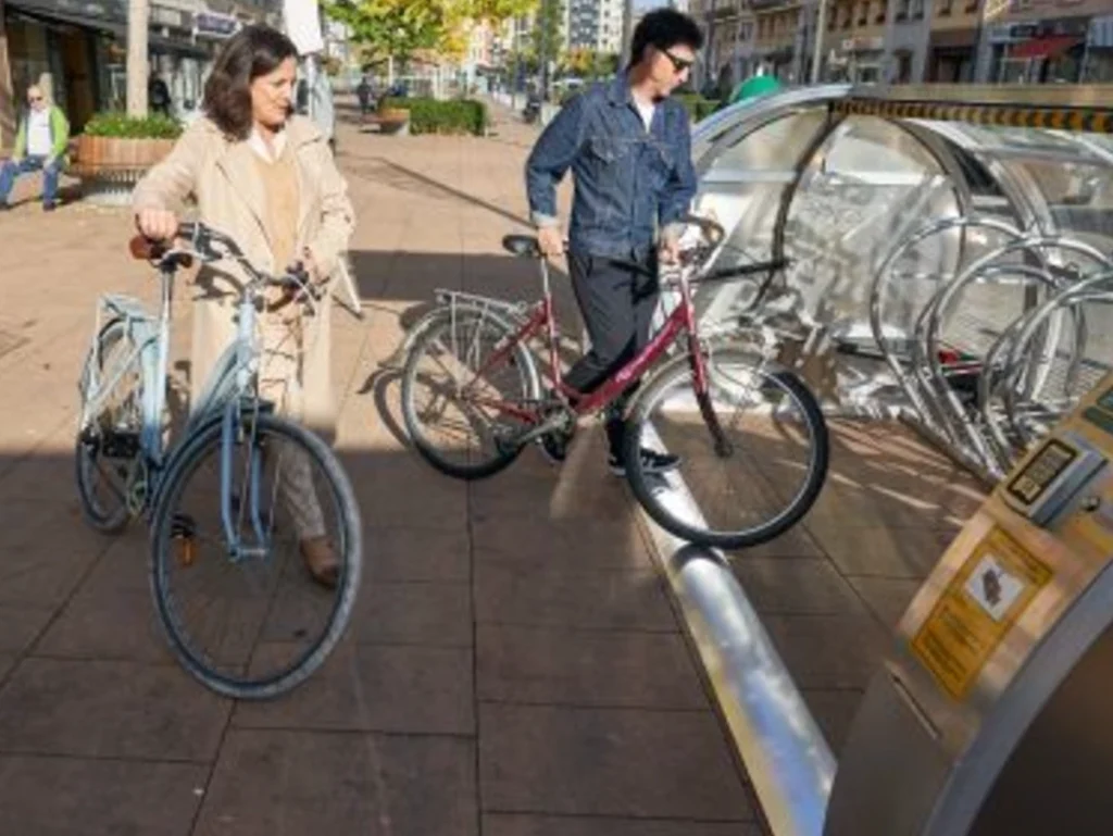 Dos personas con bicicletas en un aparcamiento seguro al aire libre.