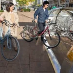 Dos personas con bicicletas en un aparcamiento seguro al aire libre.