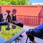 Tres personas durante una entrevista al aire libre en un patio.
