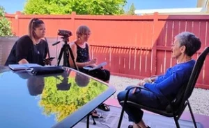 Tres personas durante una entrevista al aire libre en un patio.