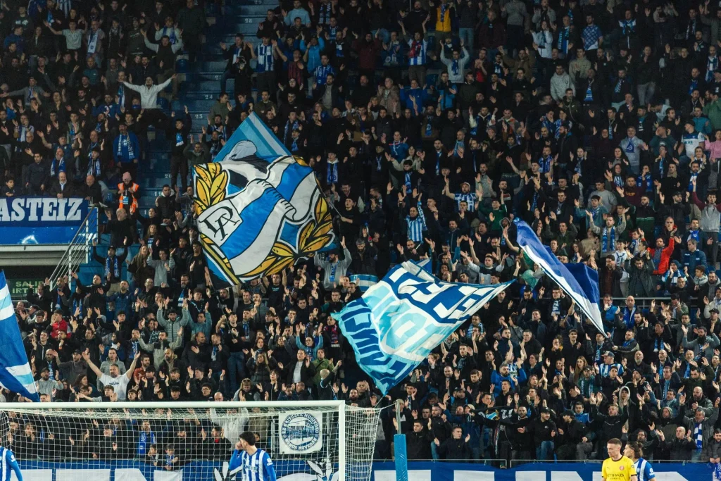 Aficionados del Alavés animando con banderas en un estadio