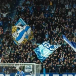Aficionados del Alavés animando con banderas en un estadio