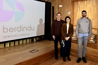 Tres personas posan frente a un logo de Berdindu en un evento