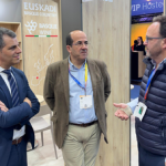Tres hombres conversando en un stand de bodegas vascas