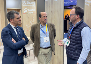 Tres hombres conversando en un stand de bodegas vascas