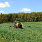 Tractor agrícola trabajando en un campo verde bajo un cielo azul