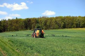 Tractor agrícola trabajando en un campo verde bajo un cielo azul
