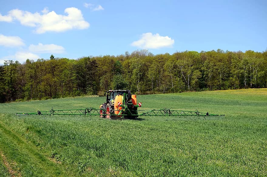Tractor agrícola trabajando en un campo verde bajo un cielo azul