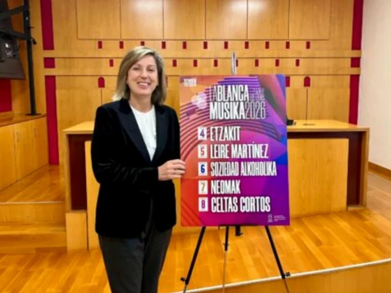Mujer sonriente junto a cartel de conciertos en La Blanca 2026.