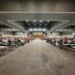 Salón amplio con mesas y numerosos aspirantes en el BEC