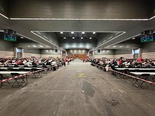 Salón amplio con mesas y numerosos aspirantes en el BEC