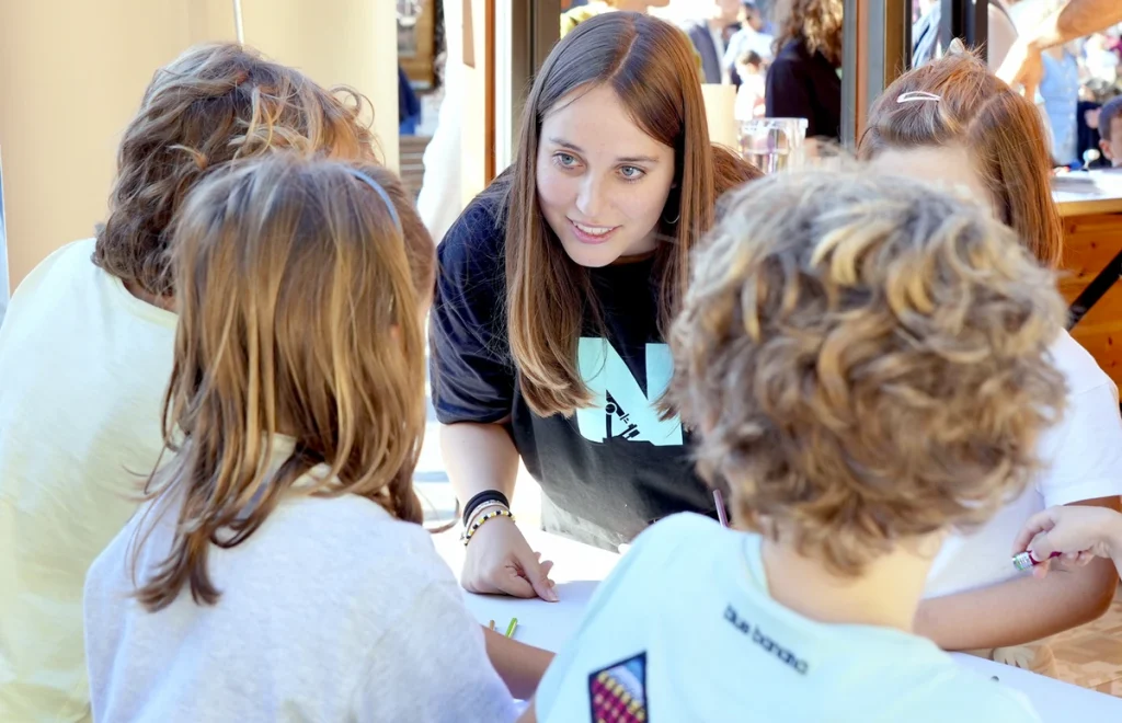 Una mujer interactuando con niños en un evento educativo.