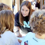 Una mujer interactuando con niños en un evento educativo.