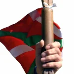 Persona sosteniendo un bastón con una bandera vasca de fondo