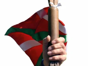 Persona sosteniendo un bastón con una bandera vasca de fondo