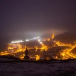 Vista nocturna de un pueblo iluminado con niebla