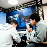 Tres personas conversando en el stand de EUNEIZ en un congreso