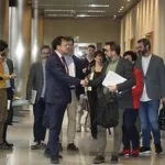 Grupo de personas en un pasillo, algunas con documentos en mano.