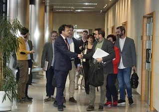 Grupo de personas en un pasillo, algunas con documentos en mano.