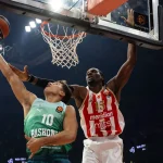 Jugador de Baskonia intenta encestar mientras es bloqueado por un jugador de Estrella Roja.