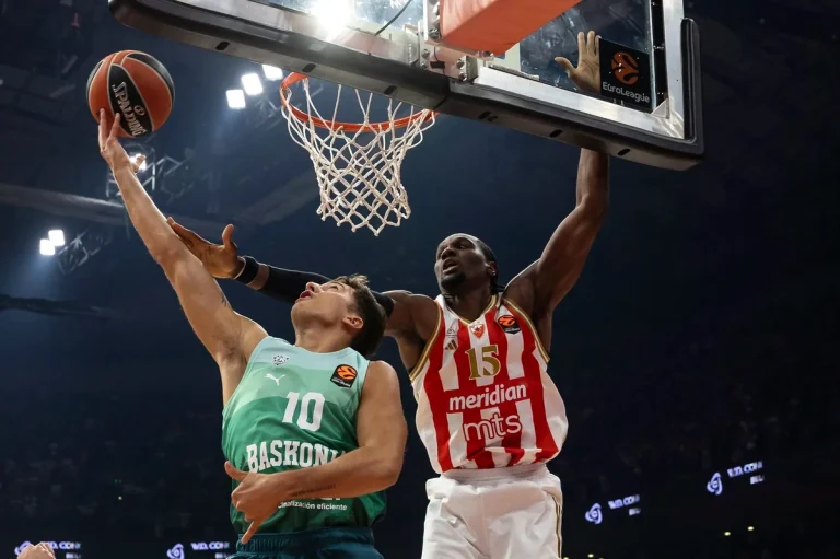 Jugador de Baskonia intenta encestar mientras es bloqueado por un jugador de Estrella Roja.