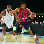 Jugador de Kosner Baskonia driblando el balón en un partido de baloncesto.