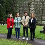 Cuatro personas posando en un parque con esculturas y vegetación