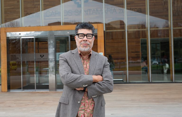 Hombre de pie frente a un edificio moderno con madera.