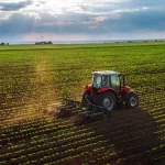 Tractor trabajando en un campo verde bajo un cielo nublado