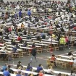 Gran cantidad de personas en un examen en un recinto amplio.